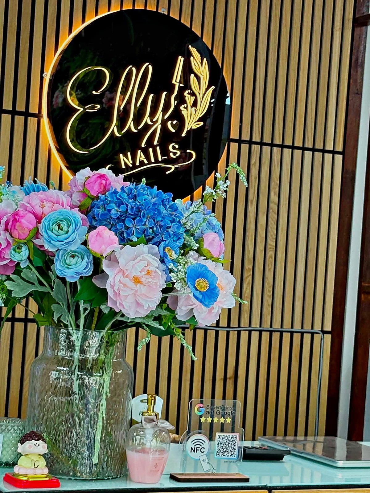Beleuchtetes Elly Nails Schild mit Blumenstrauss am Empfang in Frankfurt Ostend