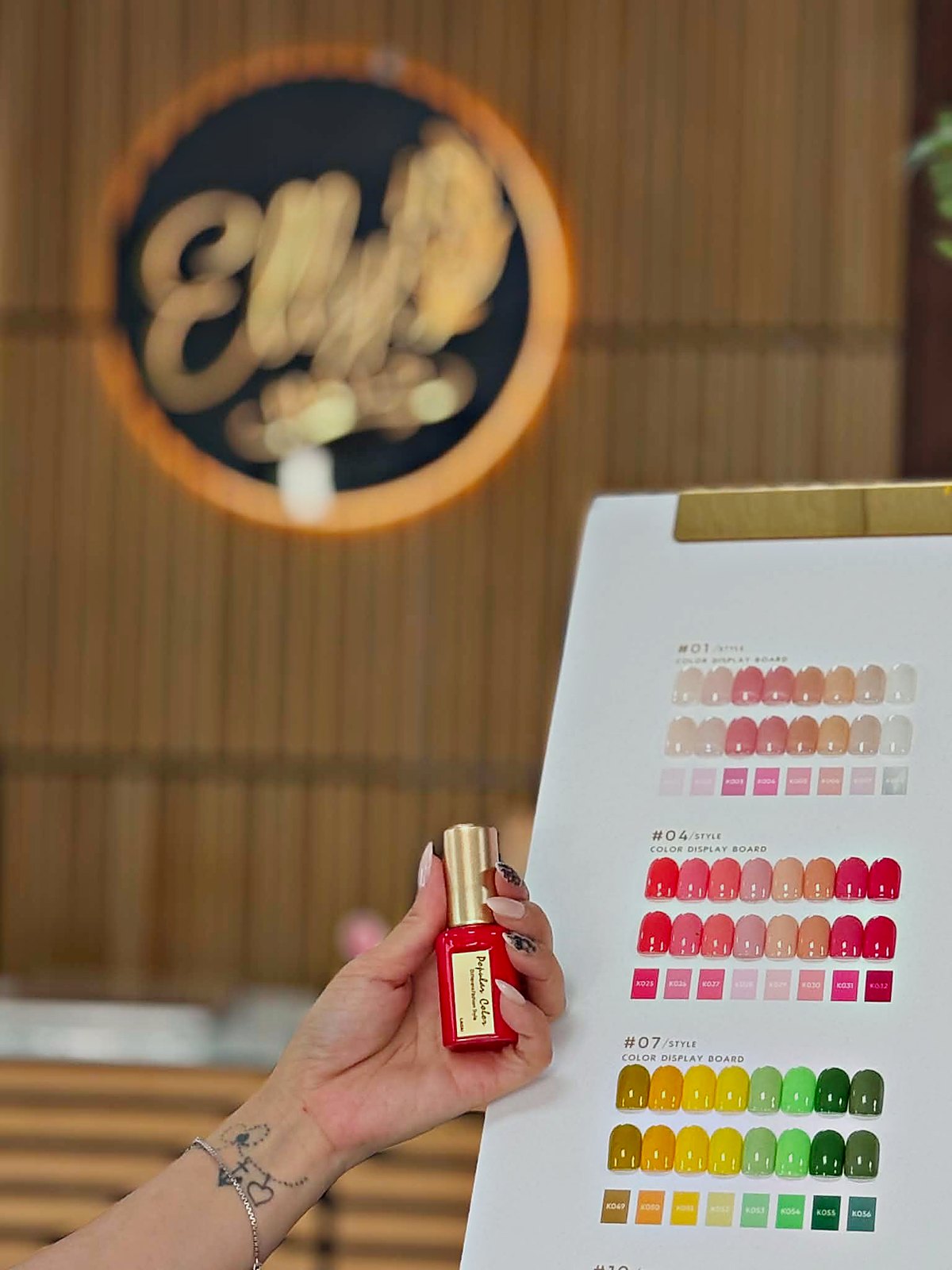 Farbkarte vor dem beleuchteten Elly Nails Logo im Studio Frankfurt Ostend